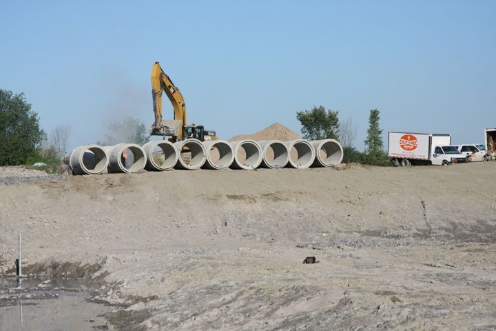 infrastructures industrielles et commerciales - Outabec Construction Gatineau-Ottawa terrain excavé avec conduites prêtes à être posées en arrière plan avec pelle mécanique et petit camion - Outabec construction